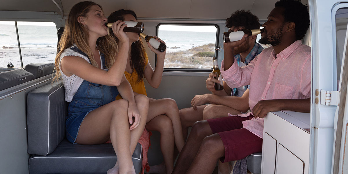 Group of friends laughing and enjoying drinks inside an RV.