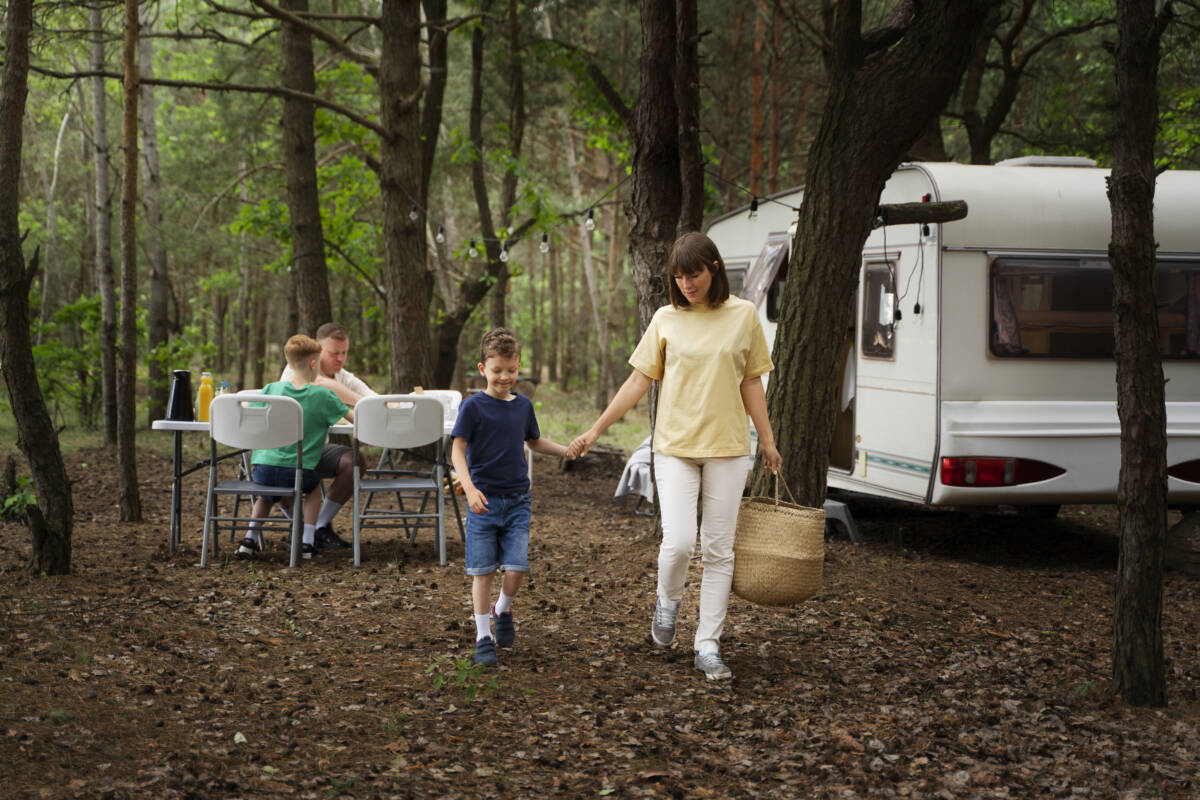 Mother and son doing chores near an RV during a family RV trip in a wooded area.