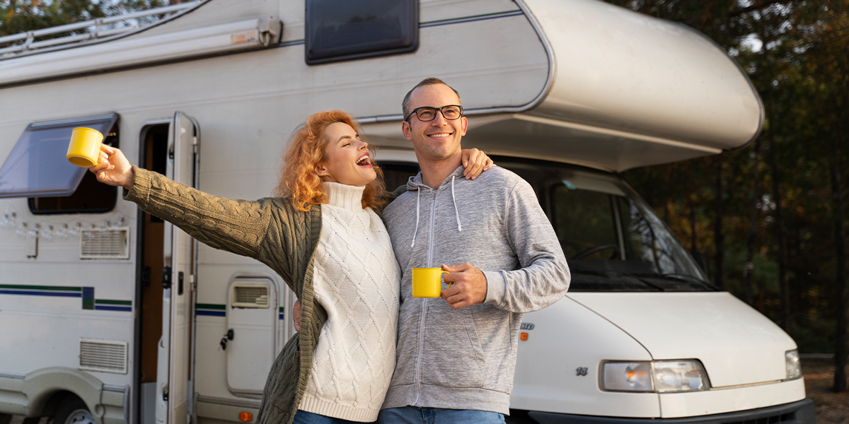 A happy couple enjoying coffee outside their motorhome during a scenic spring RV travel adventure.