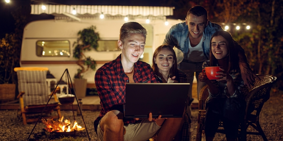 An RV parked at a scenic campground with devices connected to a router for seamless entertainment on the road.
