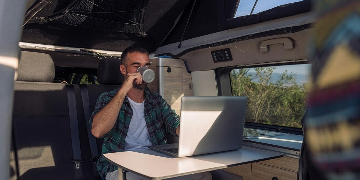 A remote worker with a laptop parked at a mountain campsite needing reliable RV Wi-Fi for work.